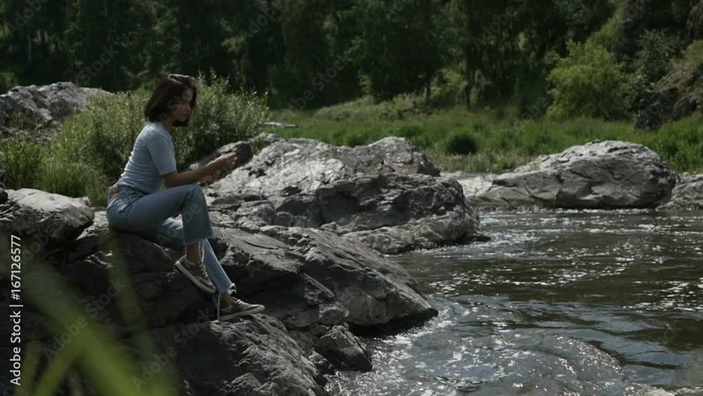Woman posing on stone on river bank Woman posing on stone on river bank