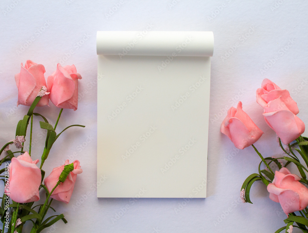 Flat lay with notepad and roses on white background. Romantic banner template with text place.