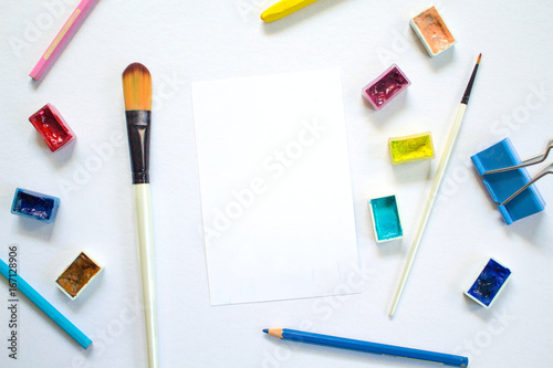 White paper notepad and drawing art supplies. Colorful artistic flat lay on white background.