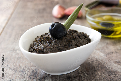 Black olive tapenade with anchovies, garlic and olive oil on wooden table
 photo