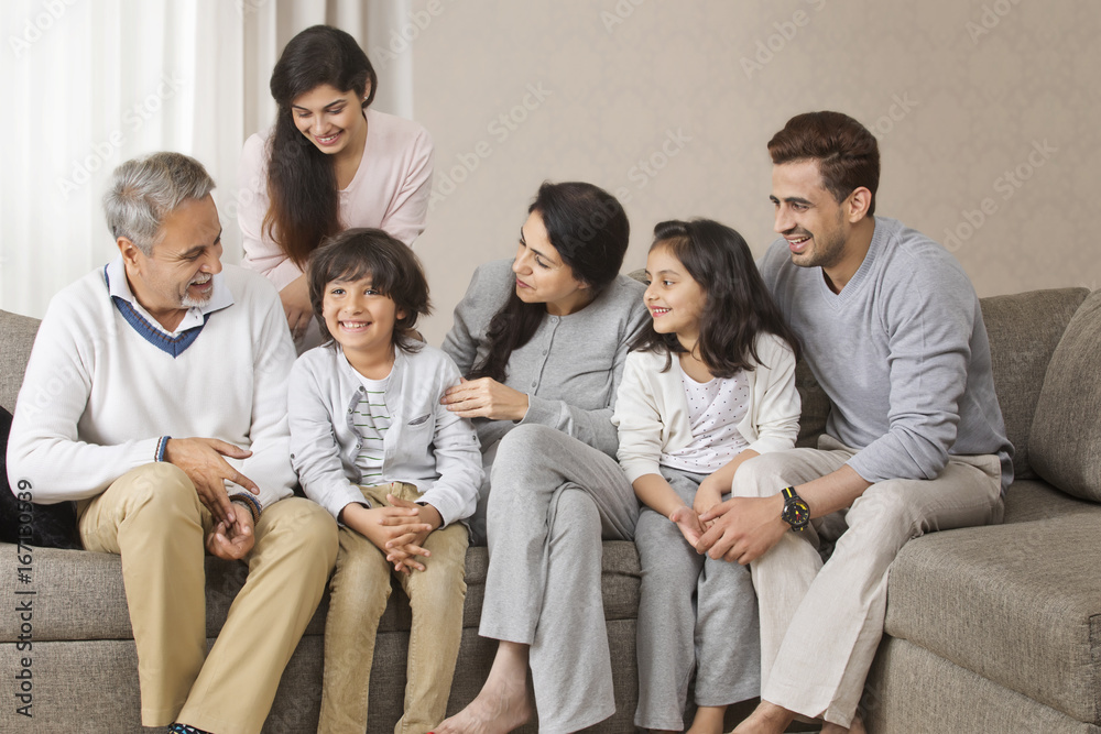 Happy multi-generation family sitting together on sofa Happy multi-generation family sitting together on sofa