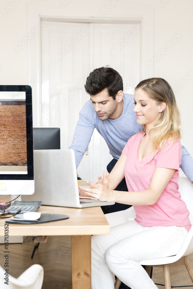 Business group at work. Shot of two young business people sitting in front of laptop and consulting while working on new project. Teamwork. Business group at work. Shot of two young business people sitting in front of laptop and consulting while working on new project. Teamwork.