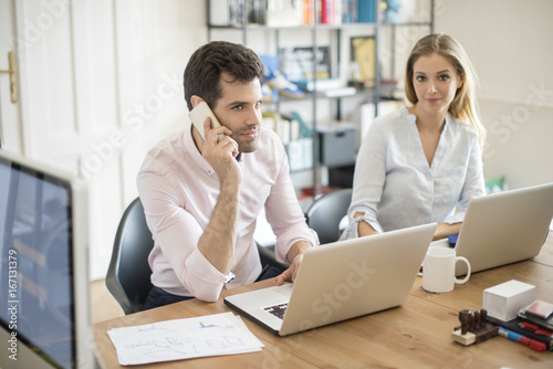 Business group at work. Shot of two young business people sitting in front of laptop and consulting while working on new project. Teamwork.