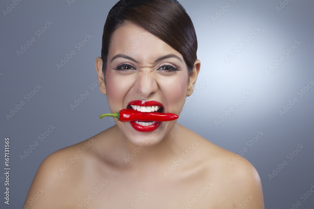 Portrait of a woman holding red pepper in teeth Portrait of a woman holding red pepper in teeth