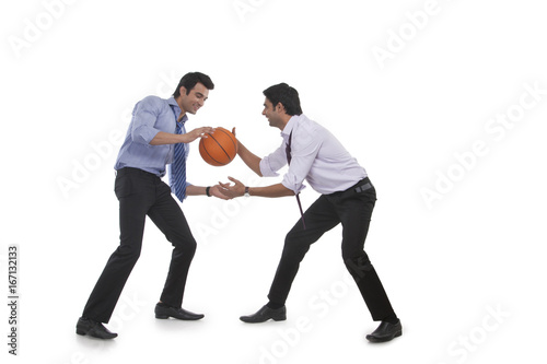 Two male executives playing basketball