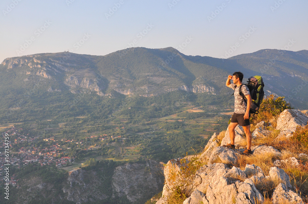 Young man sits on a cliff edge on the top of mountain with gorgeous view. Dangerous Place. Adrenaline. 