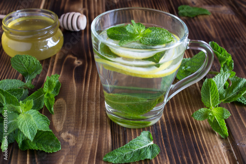 Tea with mint, lemon and honey on the wooden background