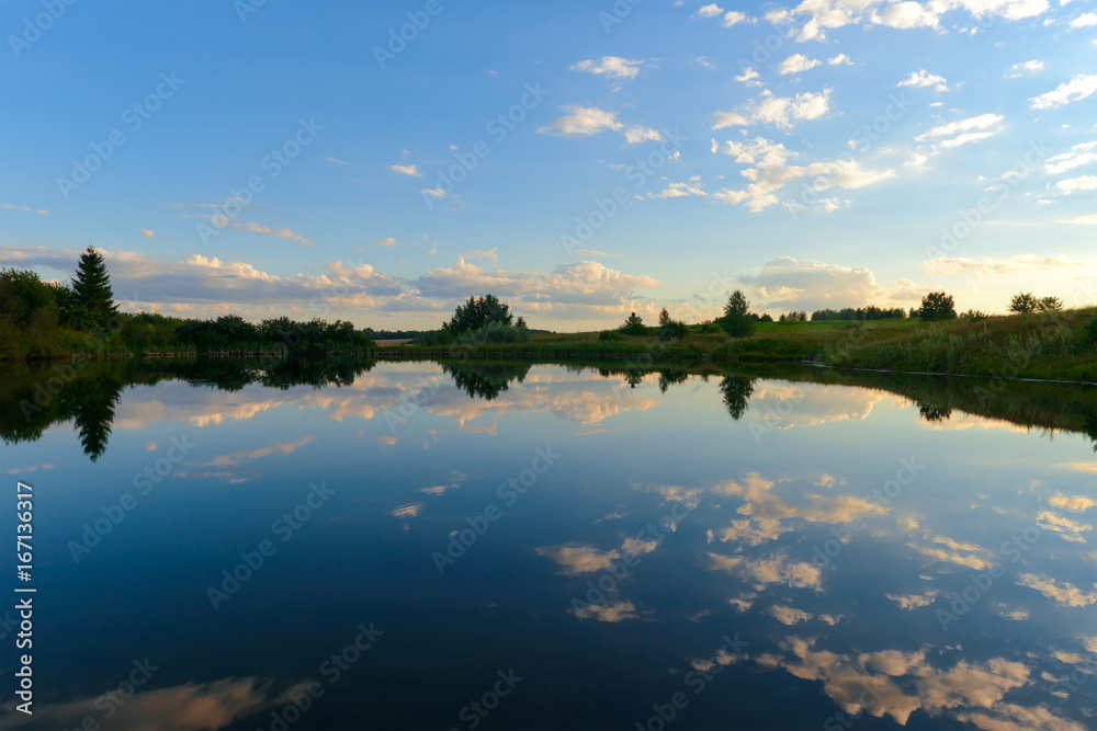 Pond with reflection of the setting sun with clouds