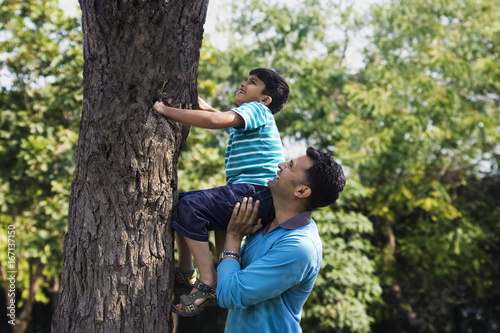 Father helping his son climb a tree  © IndiaPix