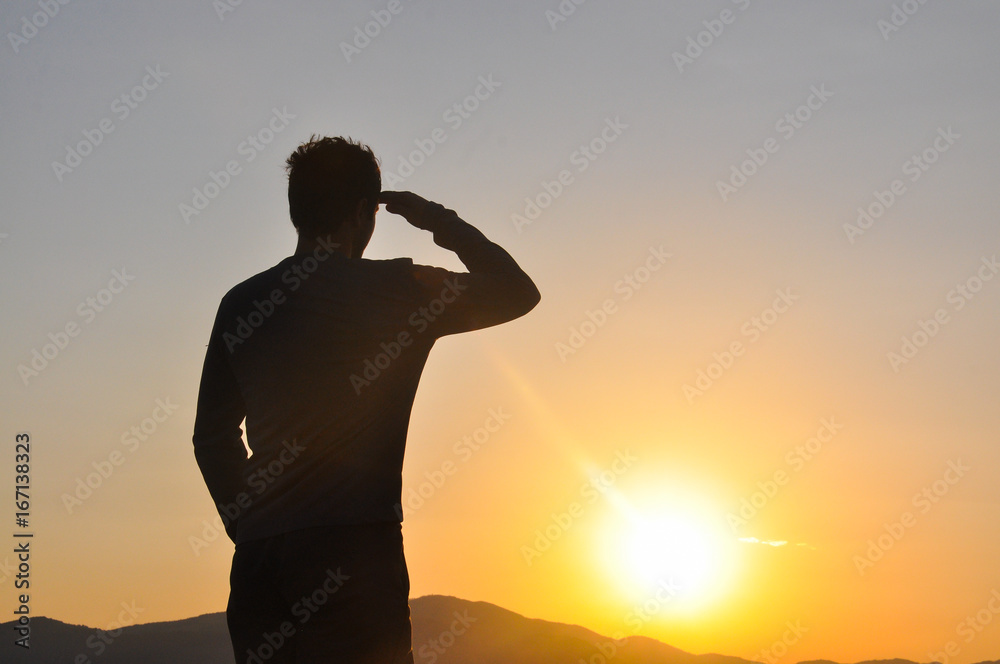Silhouette of man resting and watch sunrise high into a mountain. Concept of happiness and summer vacations