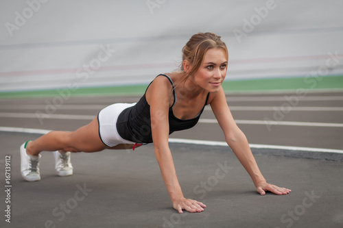 healthy lifestyle young woman runner doing push-ups on stadium