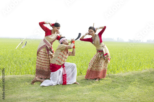 Bihu man playing on a pepa while Bihu women dance to his tune 