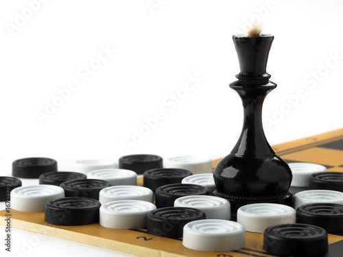The chess queen and checkers placed on the chessboard.