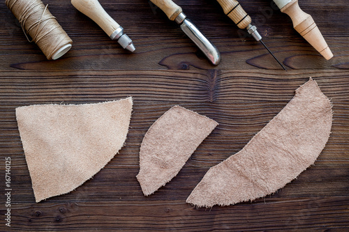 Tanner's workplace. Tools and matherials on dark wooden background top view photo