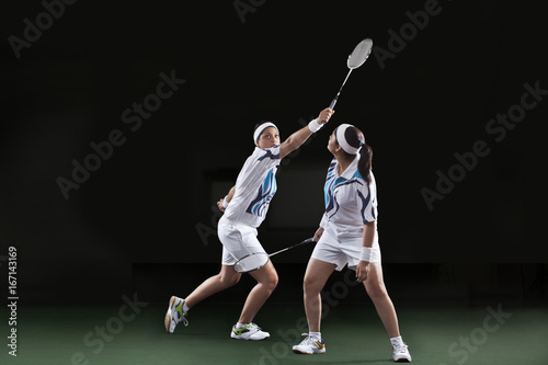 Woman looking at partner holding badminton over black background