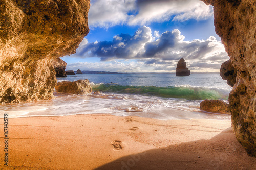 beautiful Atlantic ocean view horizon with sandy beach, rocks and waves at sunrise. Algarve, Portugal
