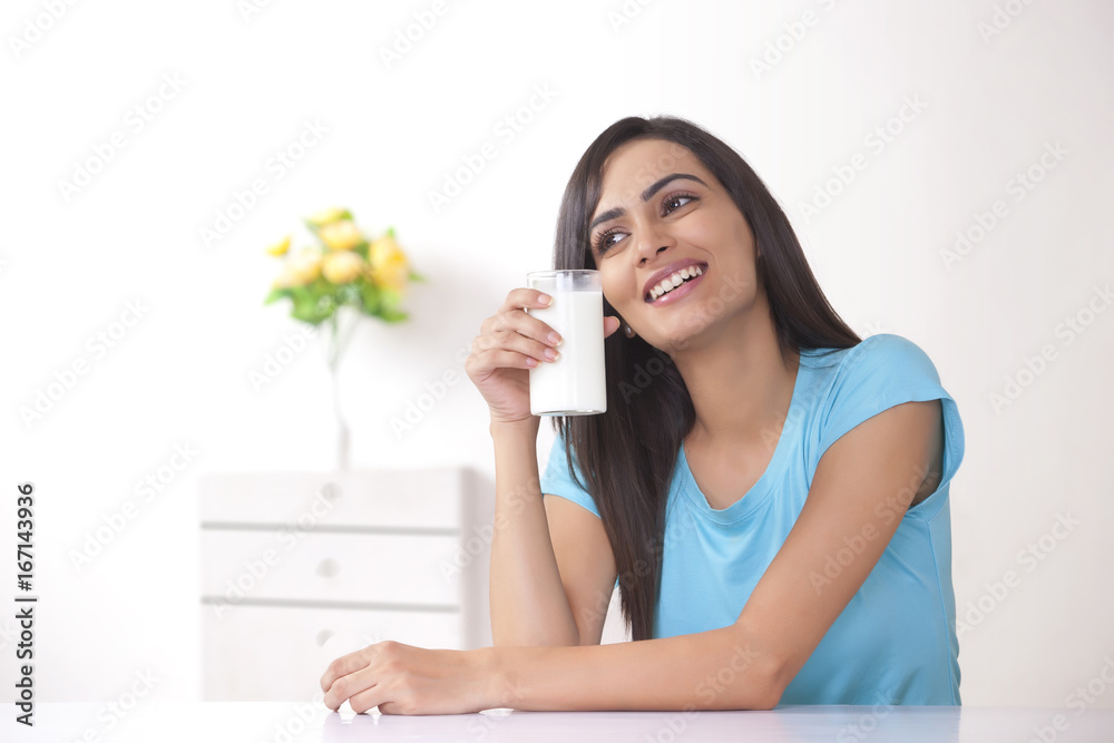 Happy young woman holding glass of milk at home Happy young woman holding glass of milk at home