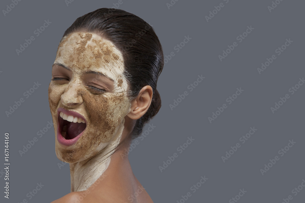 Fototapeta premium Close-up of woman with cosmetic mask over colored background 