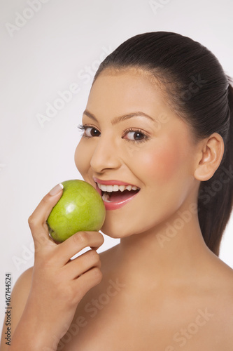Young woman eating green apple 