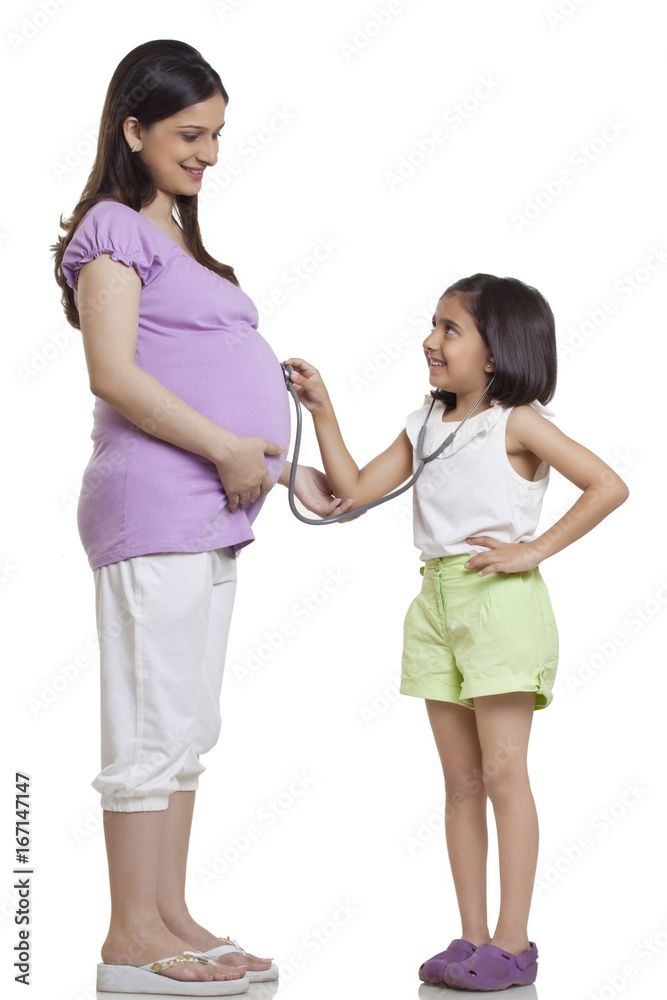 Daughter holding stethoscope to pregnant mother's stomach Daughter holding stethoscope to pregnant mother's stomach