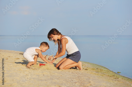 Mom plays with the baby on the beach in summer