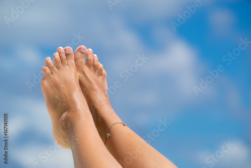 Close-up of female foot in the blue sky on the tropical beach. Vacation holidays.