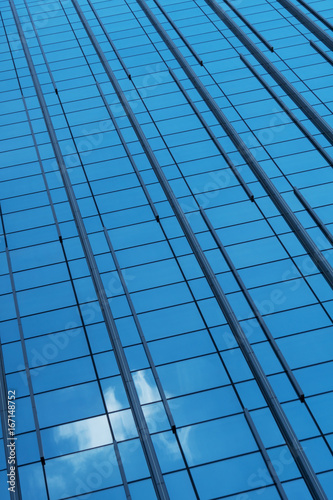 Glass facade of a building with a reflection of the sky with a cloud