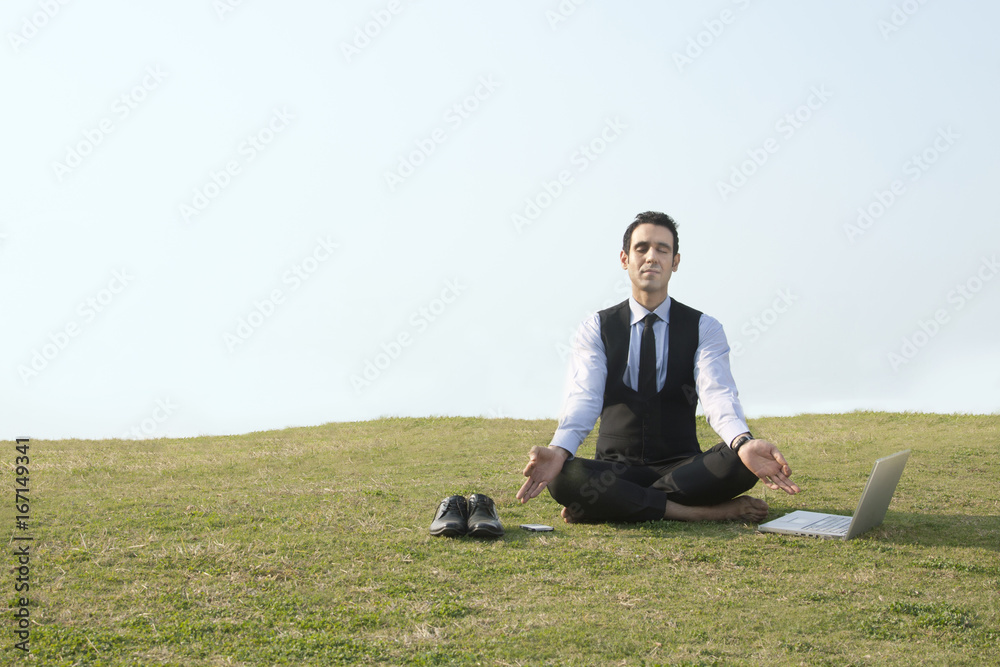 Businessman meditating outdoors , INDIA , DELHI Businessman meditating outdoors , INDIA , DELHI