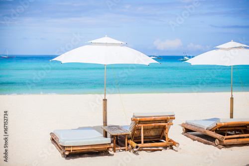 Beach chairs and umbrella on exotic tropical white sandy beach