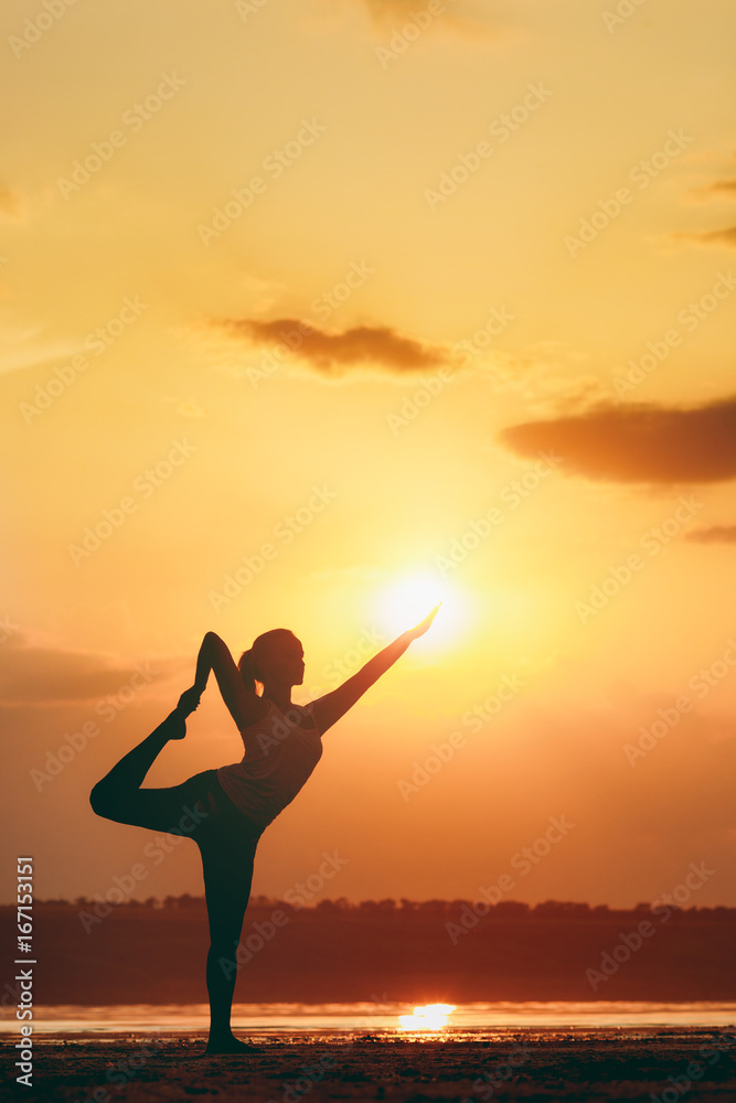 Pretty woman doing yoga at sunset outdoors