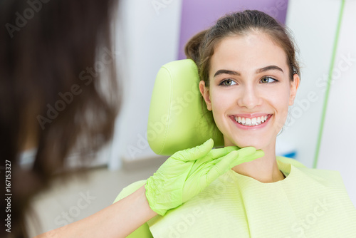 Dentist exam of young teen girl teeth.Unrecognizable doctor