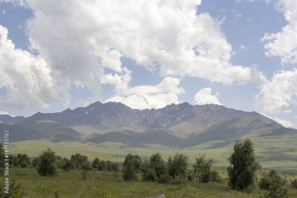 Высокая гора Эльбрус, снежные вершины в белых облаках, горы Северного Кавказа