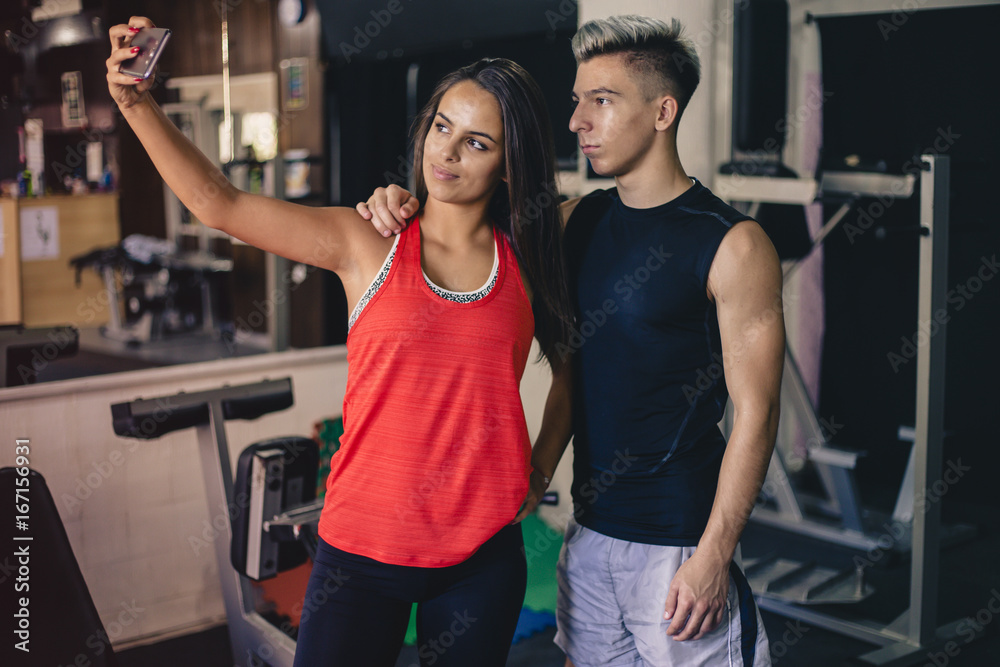Obraz premium Happy young couple taking selfie at the gym after workout