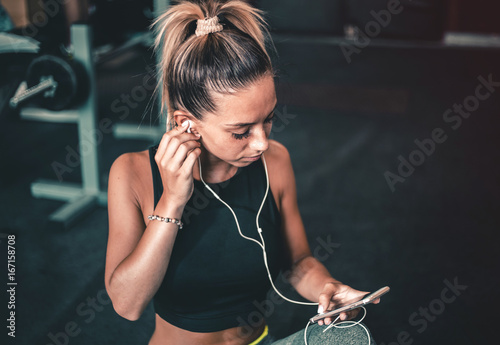 Young woman resting after workout, listening to music