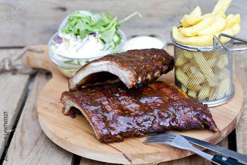 Canvas Print A plate of delicious spicy marinated grilled or barbecued ribs served with fries