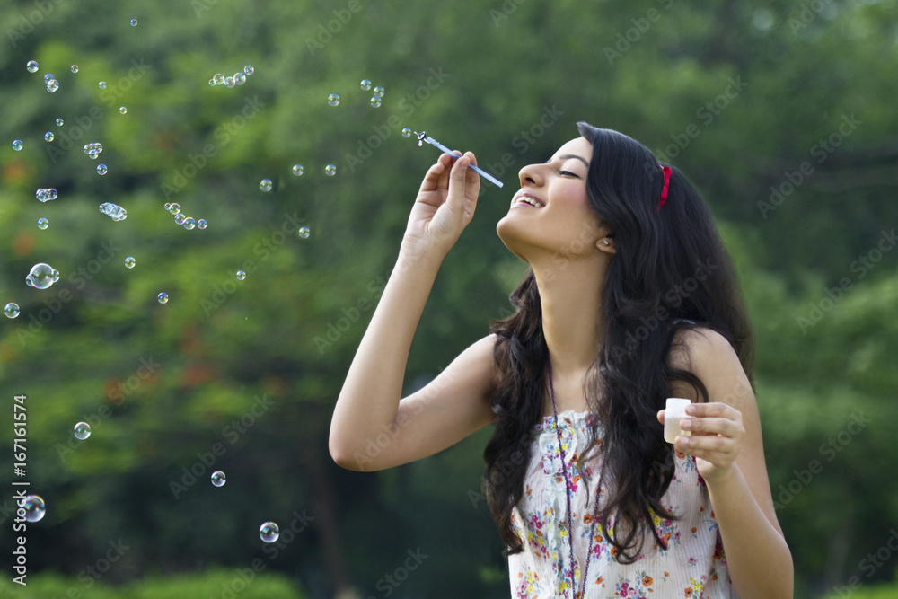Young woman blowing bubbles in a park Young woman blowing bubbles in a park