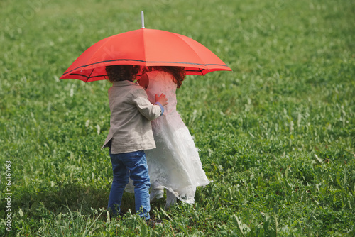 little boy and girl under red umbrella