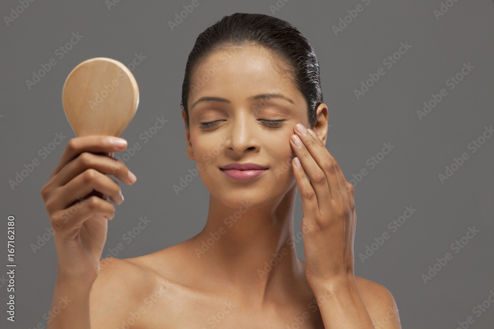 Young woman with eyes closed holding hand mirror Young woman with eyes closed holding hand mirror