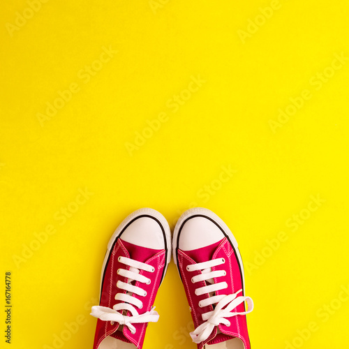 Vintage sneaker shoes in a flat lay composition over yellow background