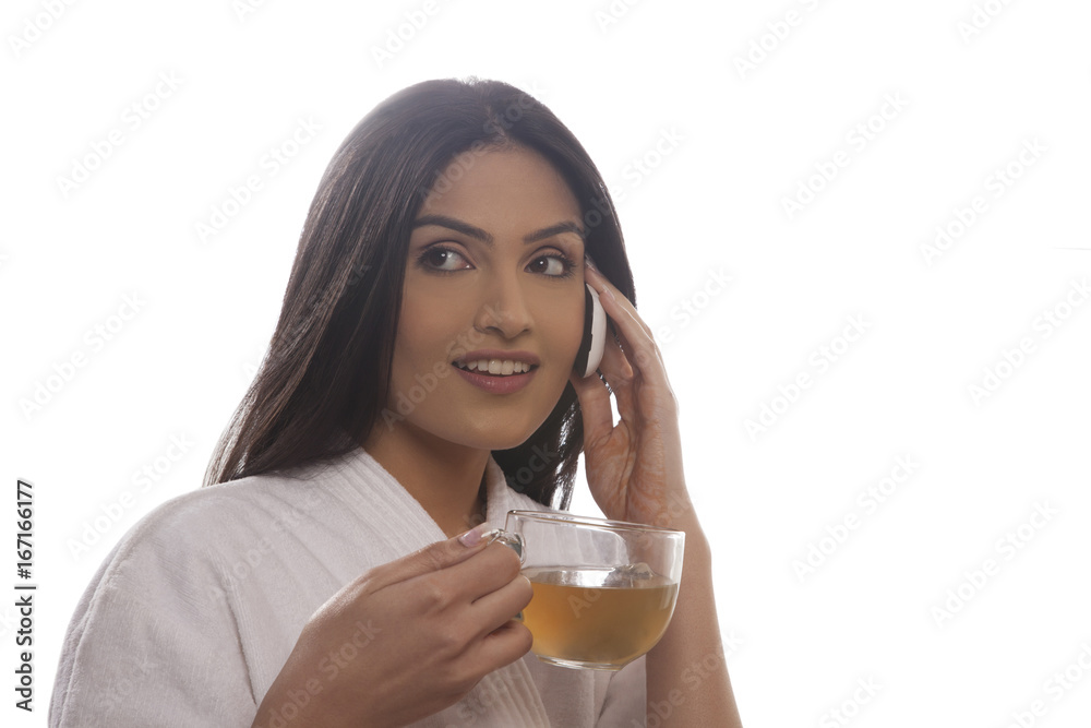 Young woman holding tea cup while using cell phone Young woman holding tea cup while using cell phone