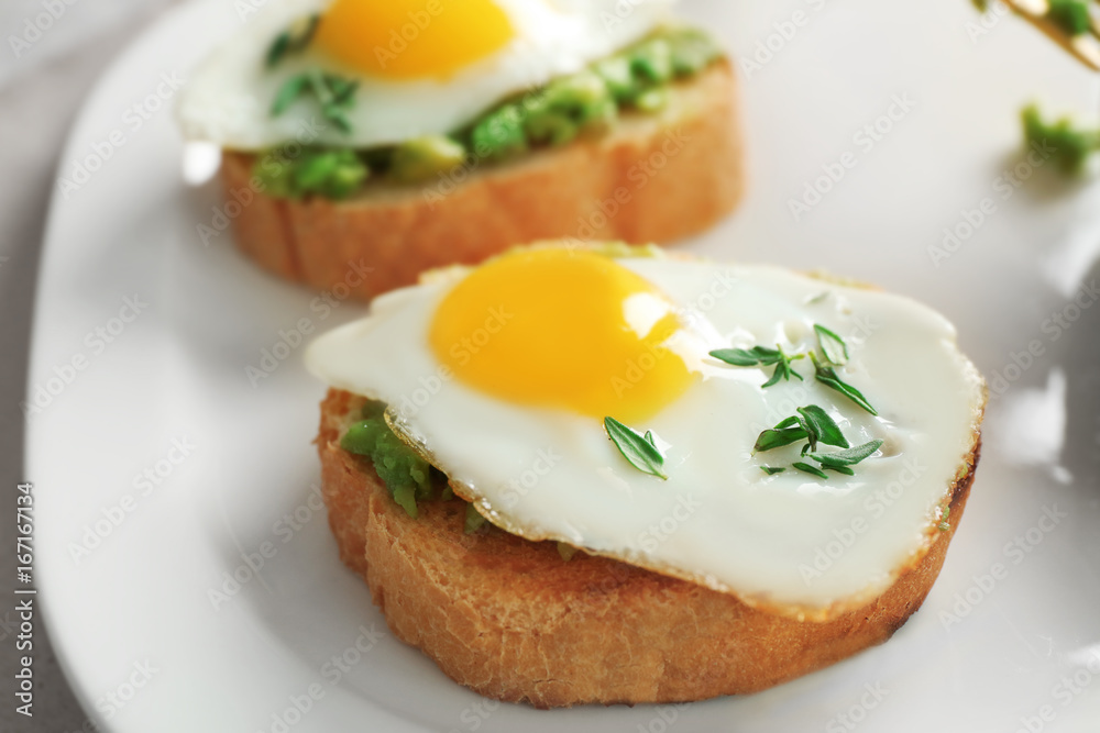 Tasty breakfast toasts with avocado and quail eggs on plate, closeup Tasty breakfast toasts with avocado and quail eggs on plate, closeup