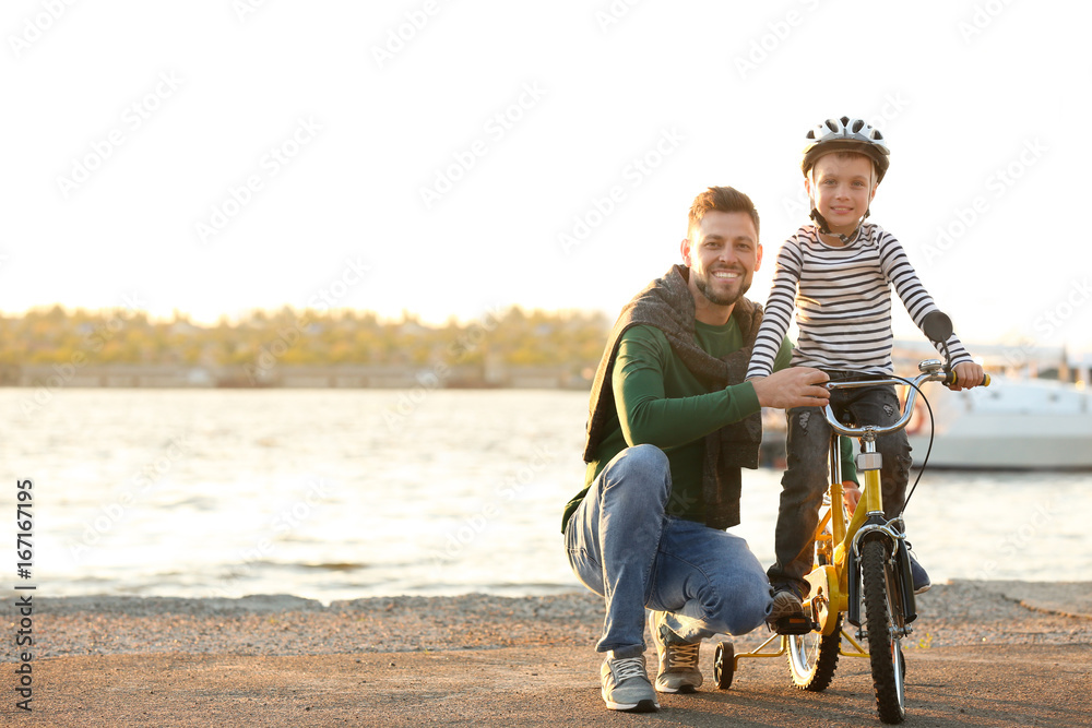 Dad teaching son to ride bicycle outdoors Dad teaching son to ride bicycle outdoors