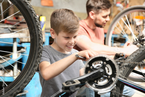 Dad and son fixing bicycles in garage
