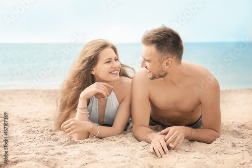 Happy young couple lying on beach