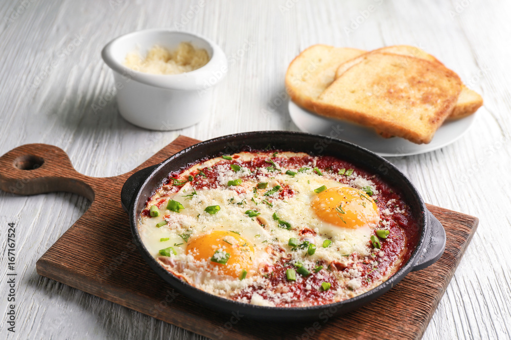 Frying pan with eggs in purgatory on wooden board Frying pan with eggs in purgatory on wooden board