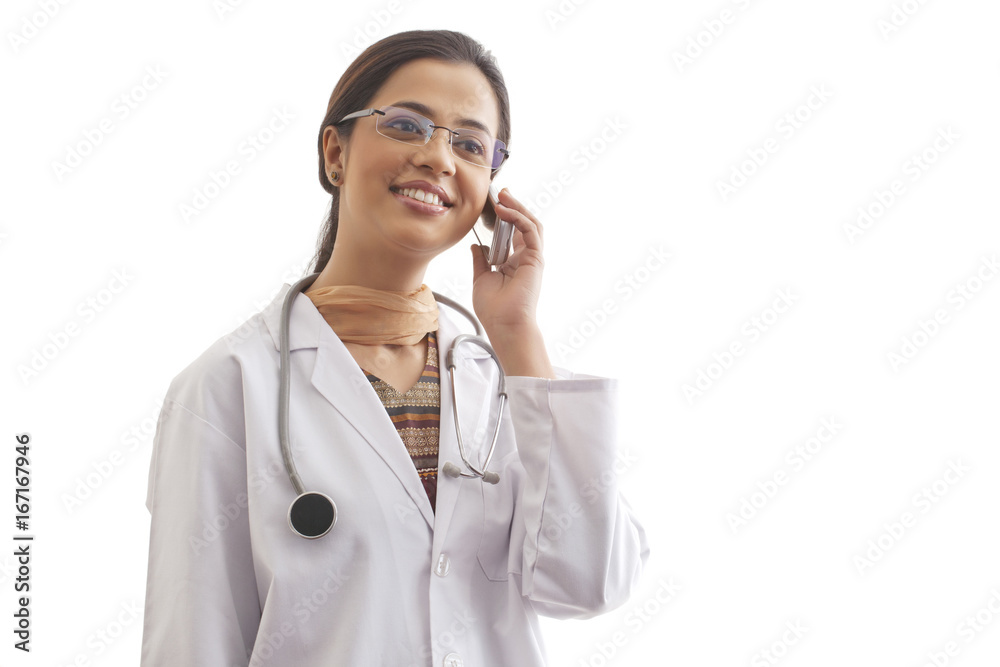 Young female doctor looking away while on call against white background Young female doctor looking away while on call against white background