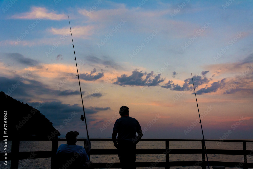 two men fishing during the sunset