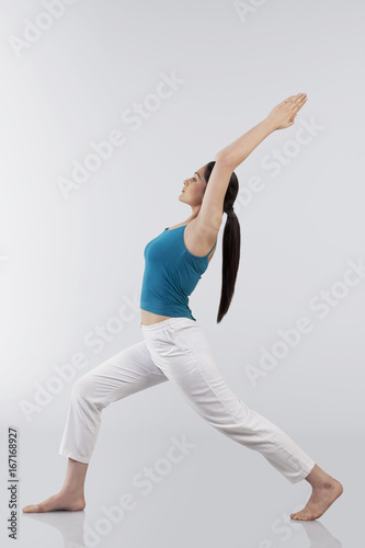 Profile shot of young woman doing back bend yoga pose on wooden floor