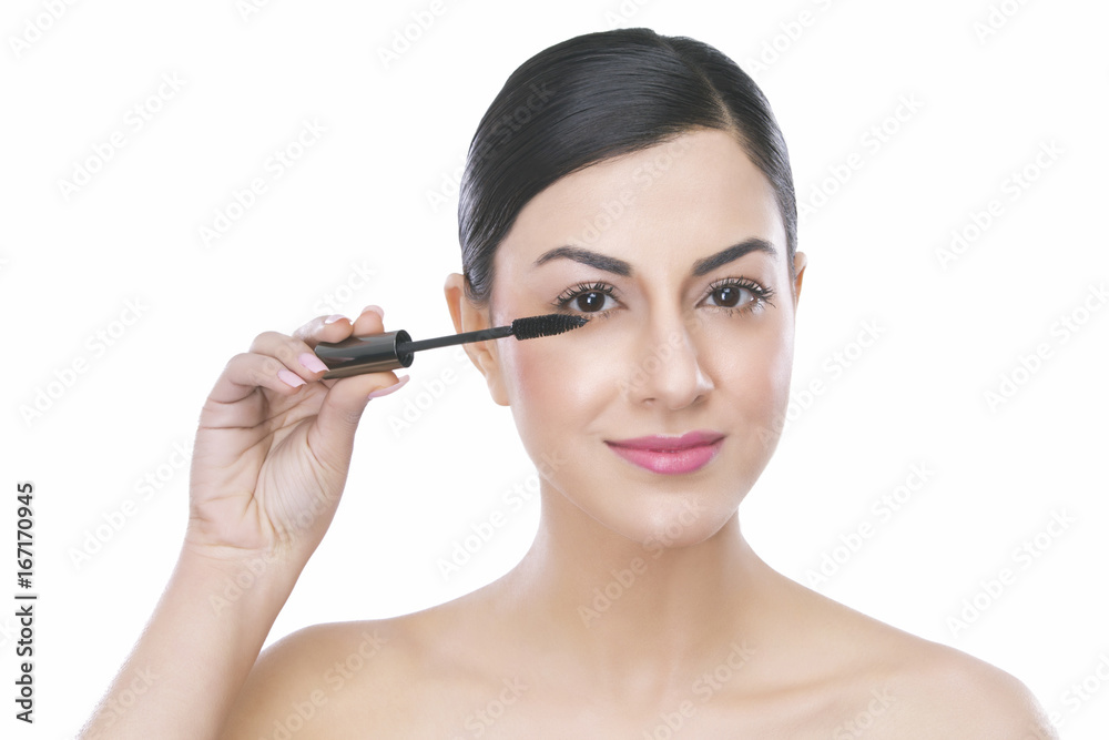 Portrait of a beautiful woman applying mascara