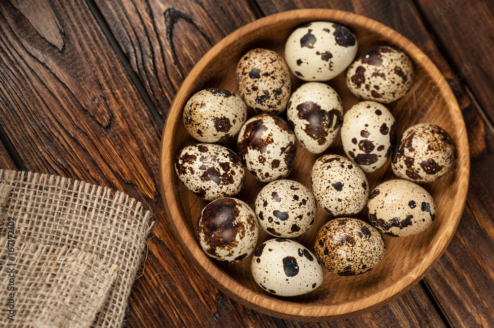 top view on quail eggs in wooden plate over old wooden background